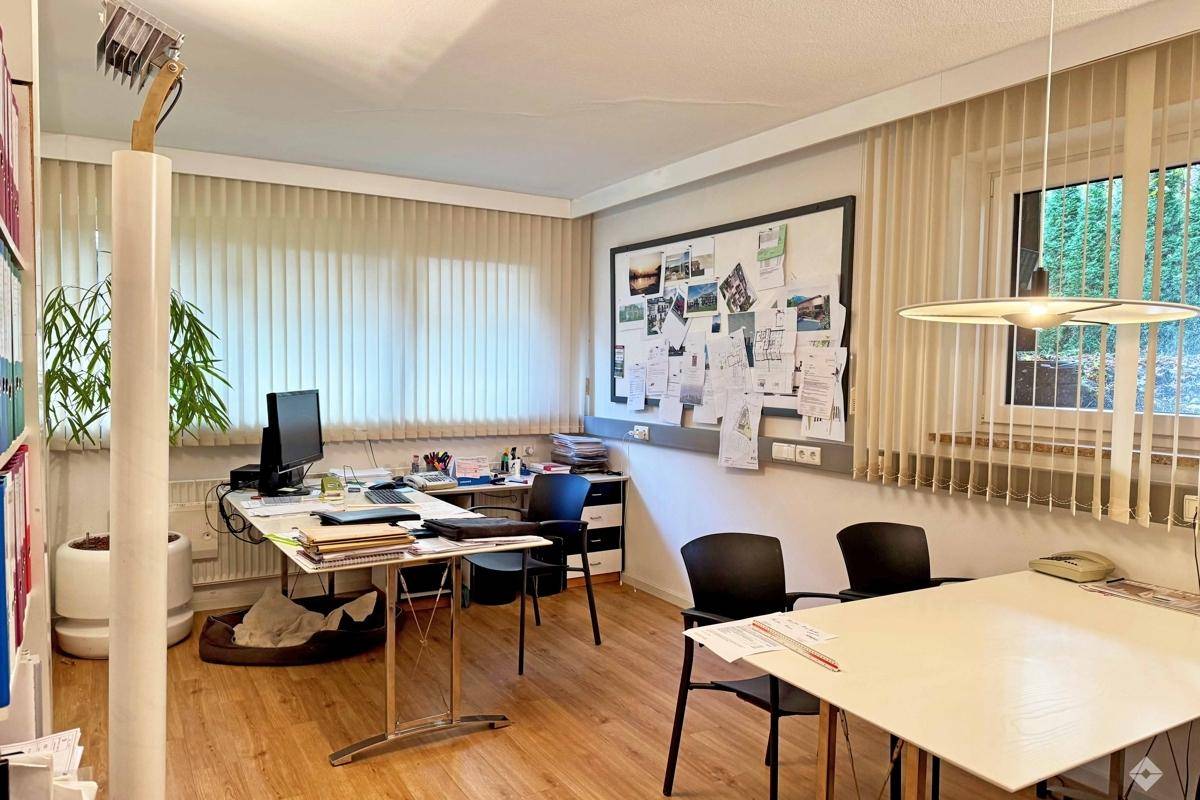 Besprechungsraum mit großem Tisch, Whiteboards und einem Großformatdrucker für technische Zeichnungen.