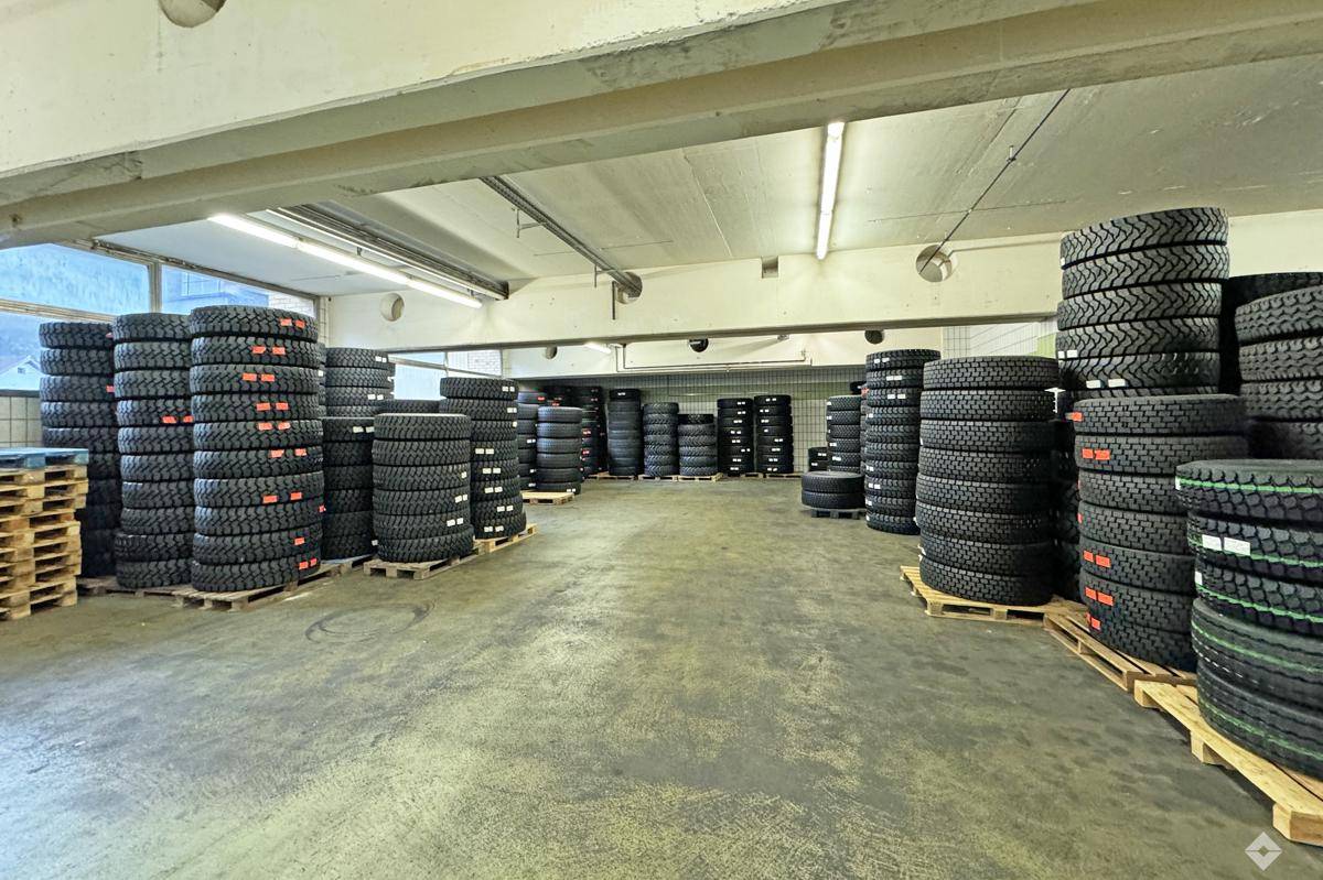 Großer Lagerbereich gefüllt mit hohen Stapeln von Reifen auf Paletten und Betonboden.