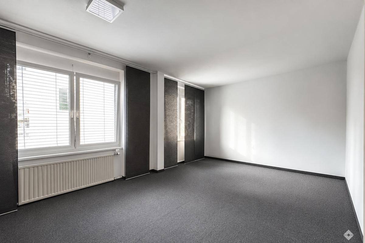 Helles, leeres Büro mit Teppichboden und Fensterfront, bereit zur individuellen Gestaltung.