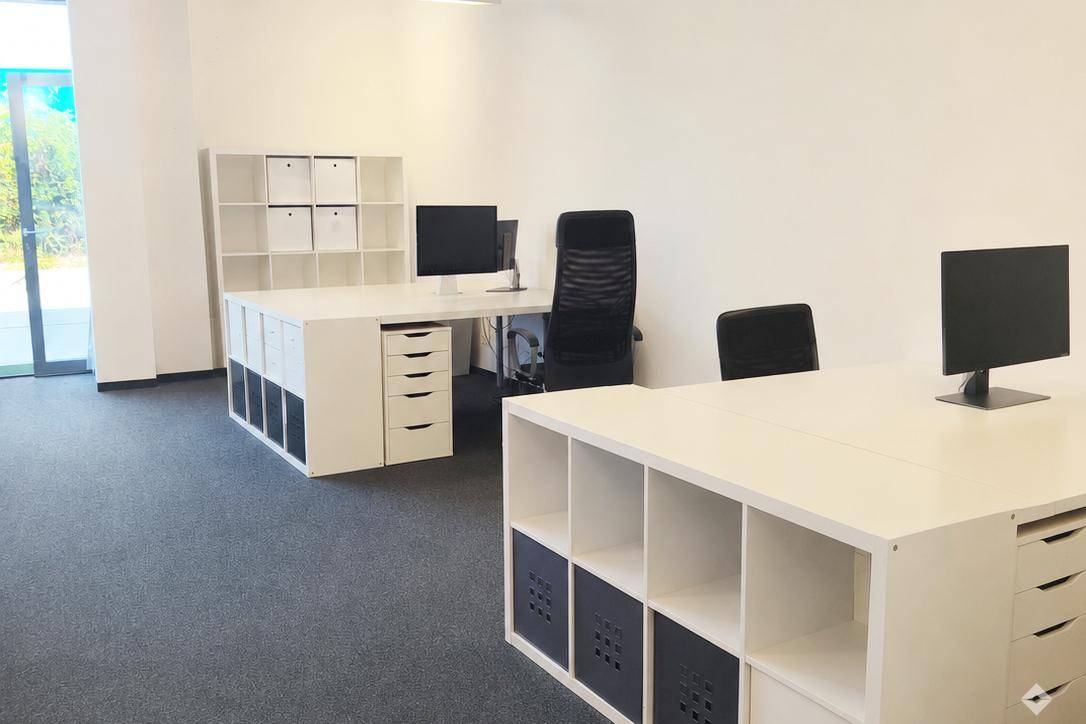 Helles Büro mit modernen weißen Schreibtischen aus Regalelementen und ergonomischen Bürostühlen.