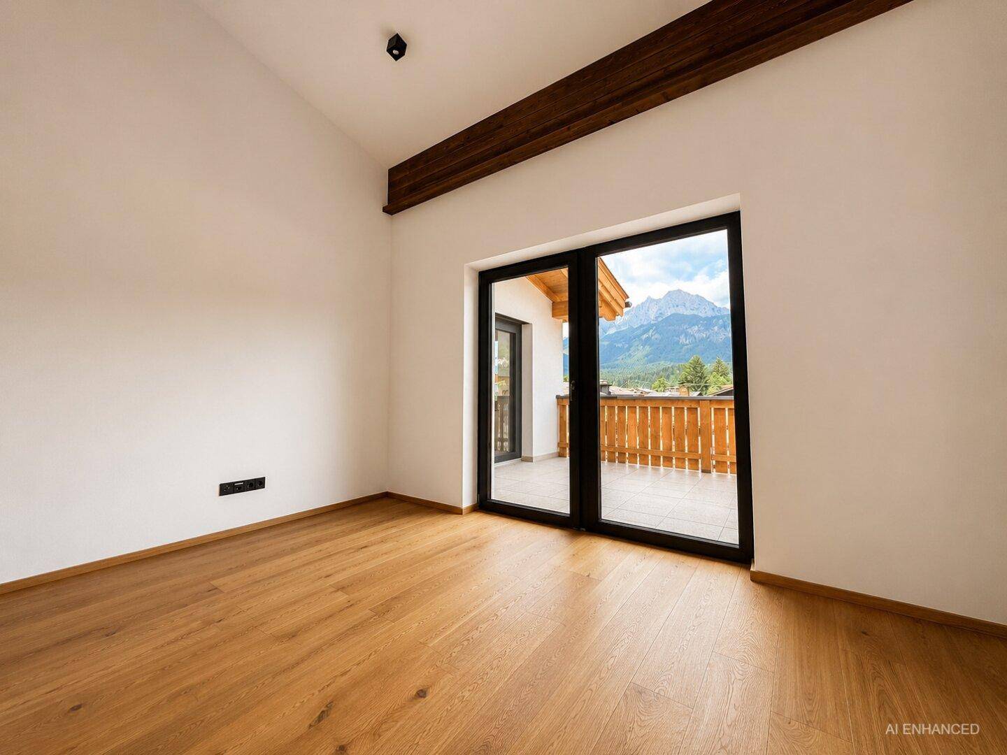 Unmöblierter Raum mit Holzboden und Zugang zu einem Balkon mit Bergblick.