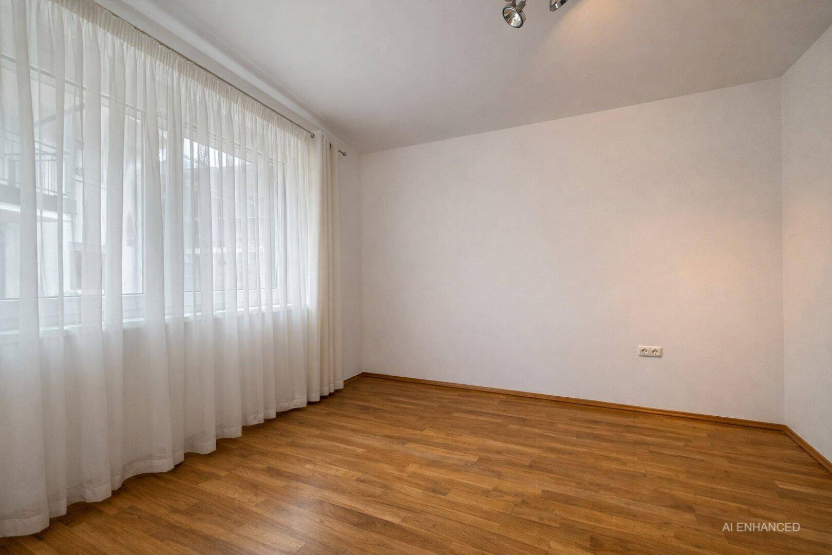 Leerer Raum mit Parkettboden und großen Fenstern, bereit zur individuellen Gestaltung.