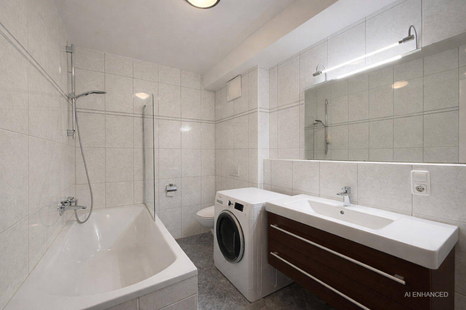 Modernes Badezimmer mit Badewanne, Dusche, Waschbecken und Waschmaschine, komplett gefliest.