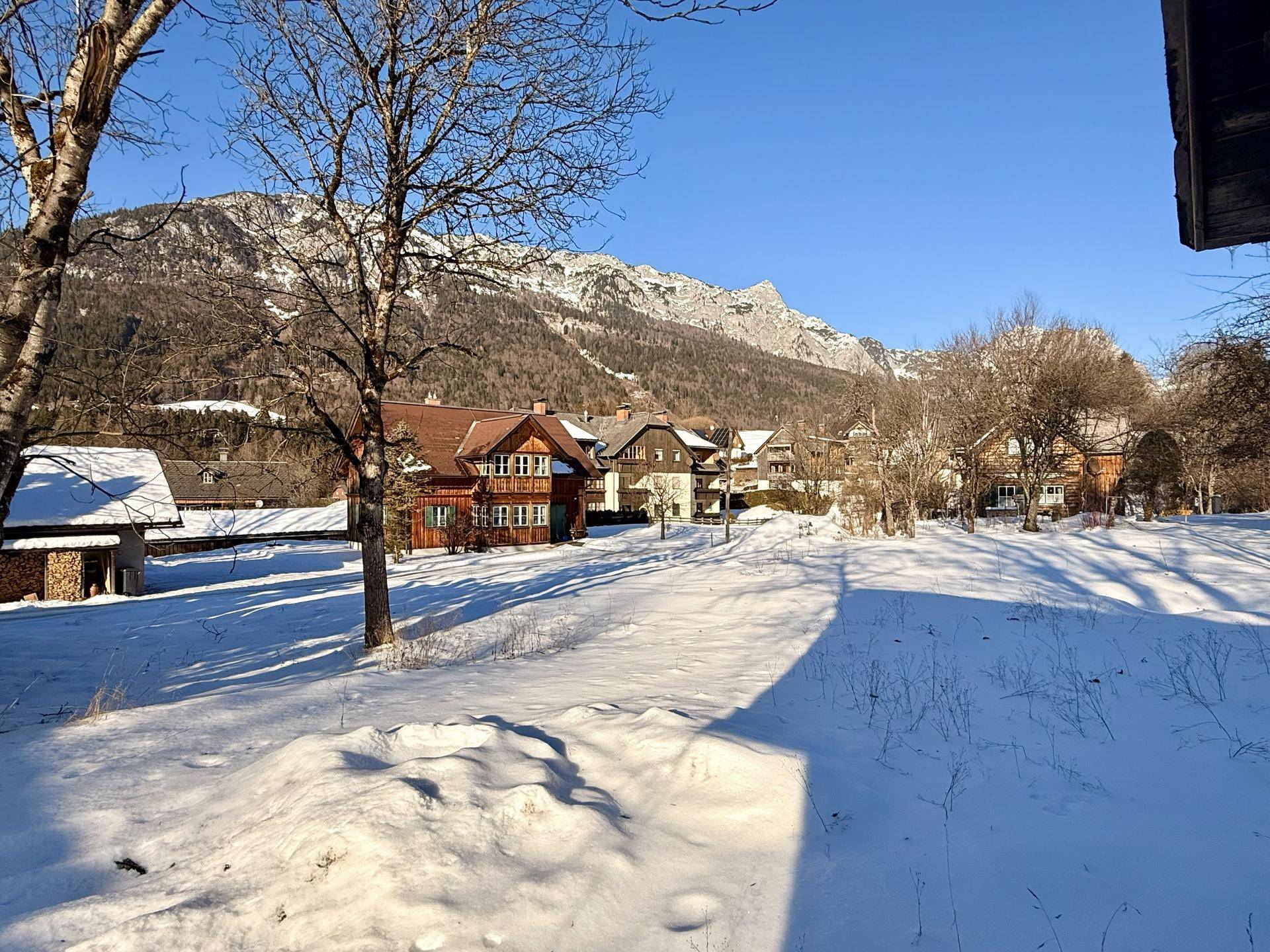 Idyllisches, schneebedecktes Grundstück mit traditionellen Häusern und majestätischem Bergblick.