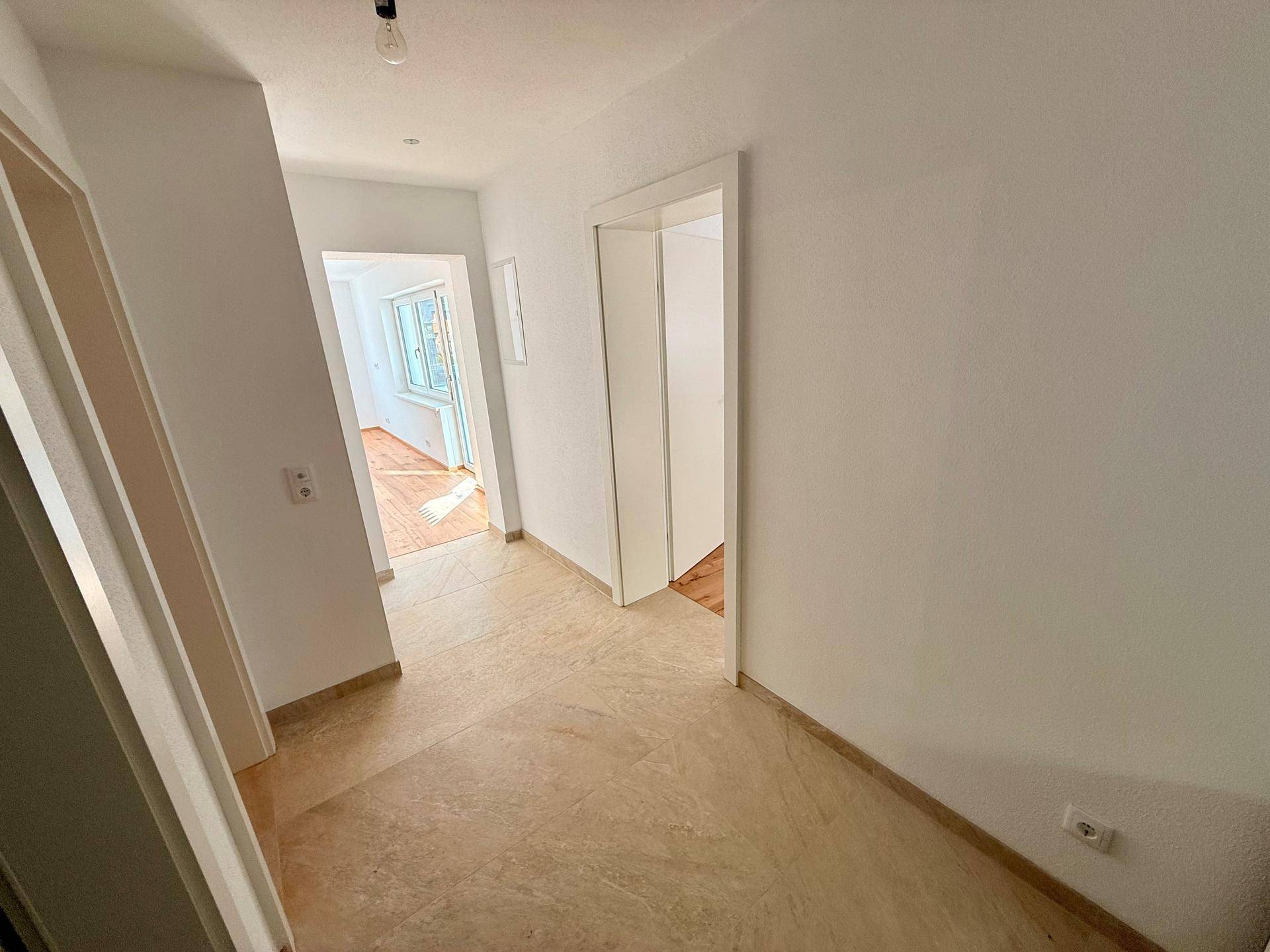Heller Flur mit beigefarbenen Fliesen, der zu den angrenzenden Wohnbereichen führt.