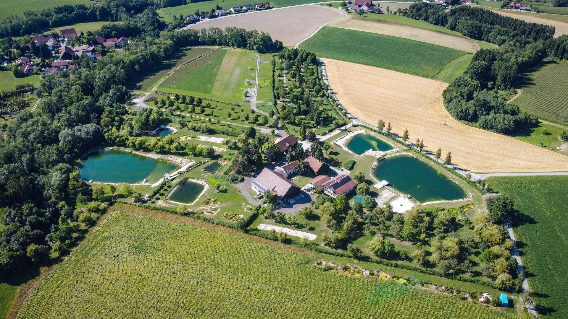 Luftaufnahme eines Anwesens mit mehreren Gebäuden, Teichen und weitläufigen Grünflächen in ländlicher Umgebung.