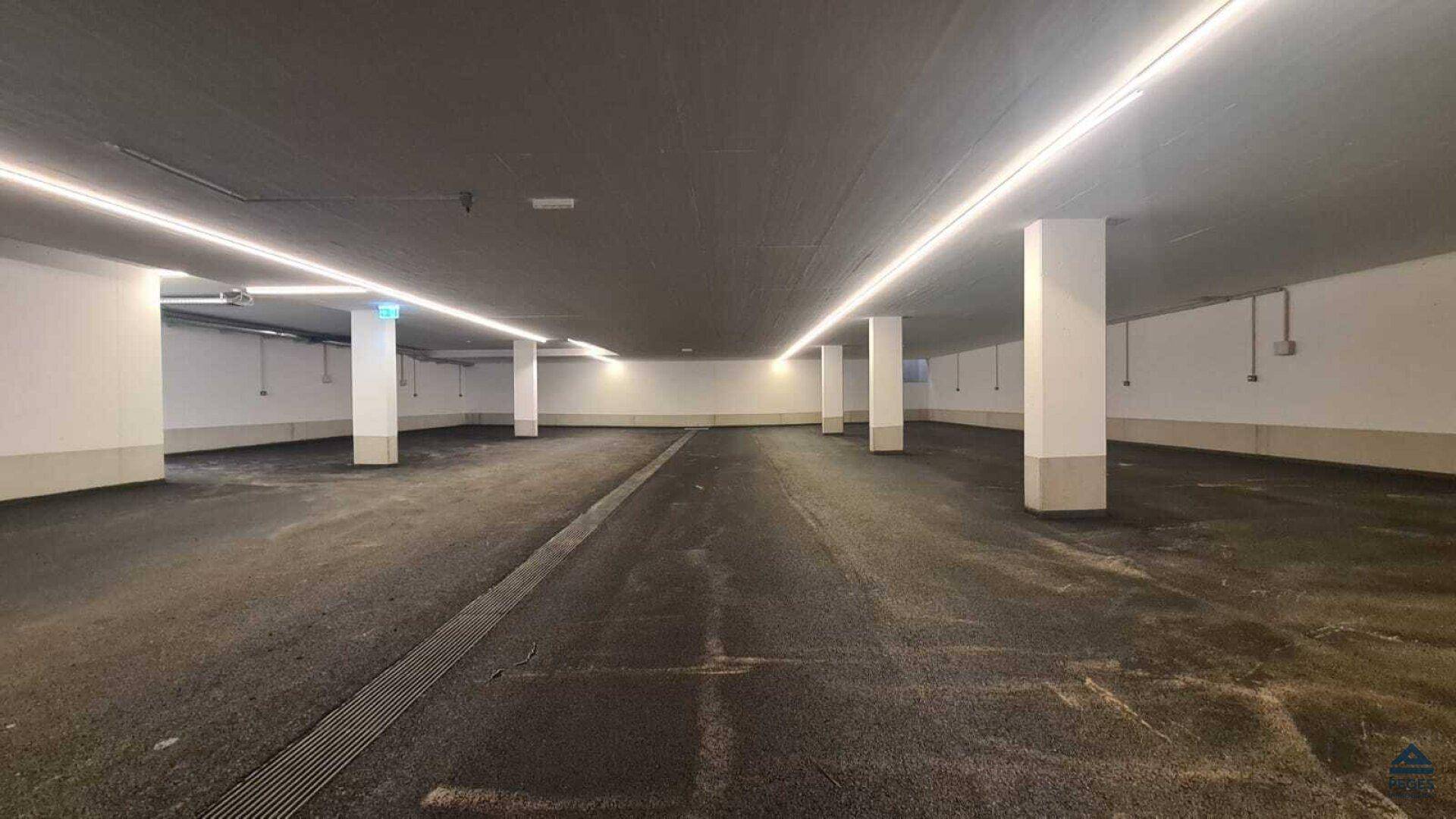 Geräumige und gut beleuchtete Tiefgarage mit vielen Stellplätzen in einem Neubau.