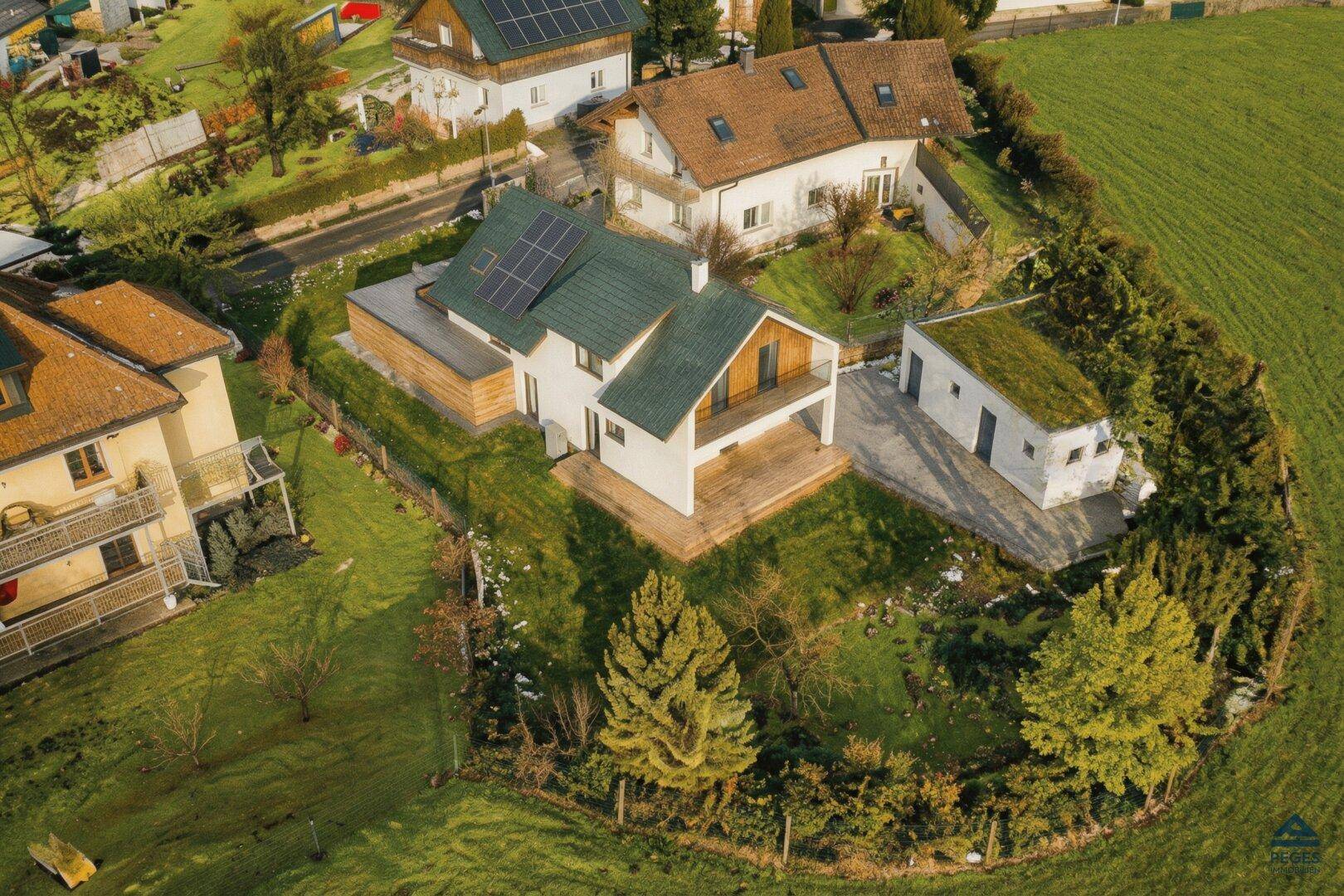 Modernes Einfamilienhaus mit Gründach, Solaranlage und gepflegtem Garten in ländlicher Umgebung.