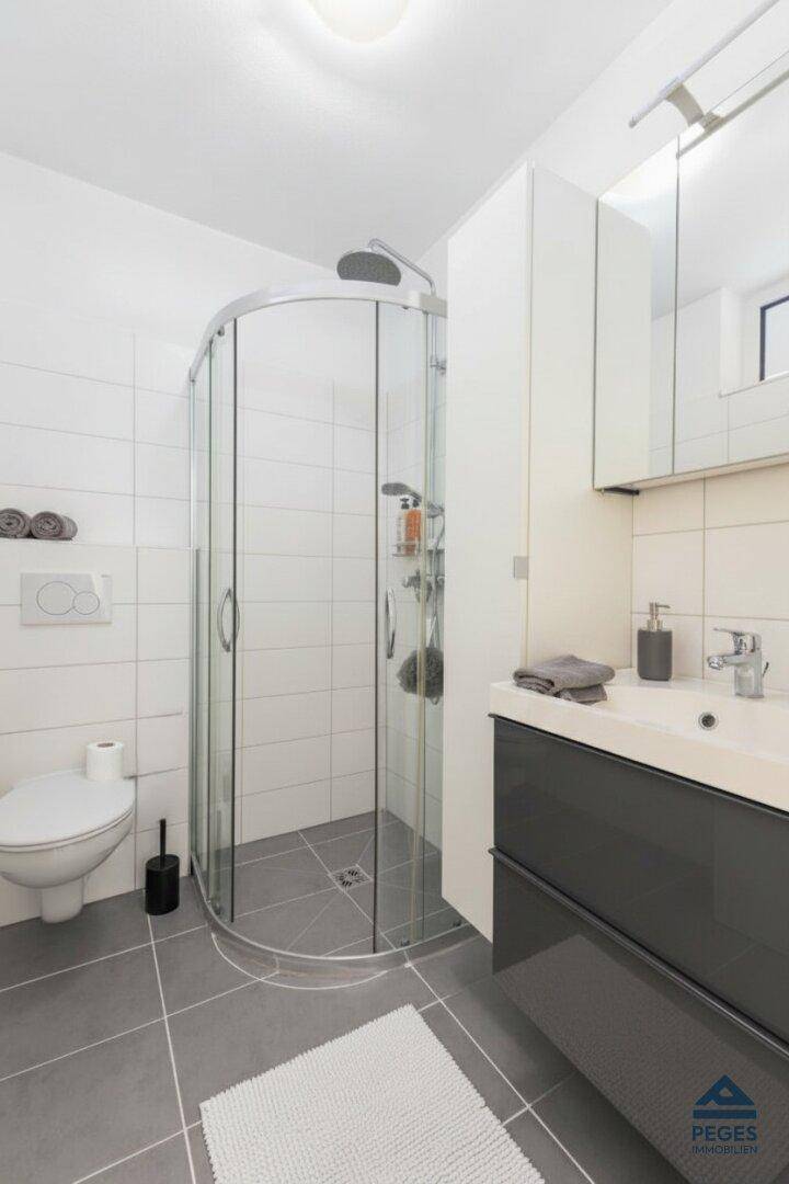 Modernes Badezimmer mit Eckdusche, wandhängendem WC und Waschtisch mit Unterschrank.