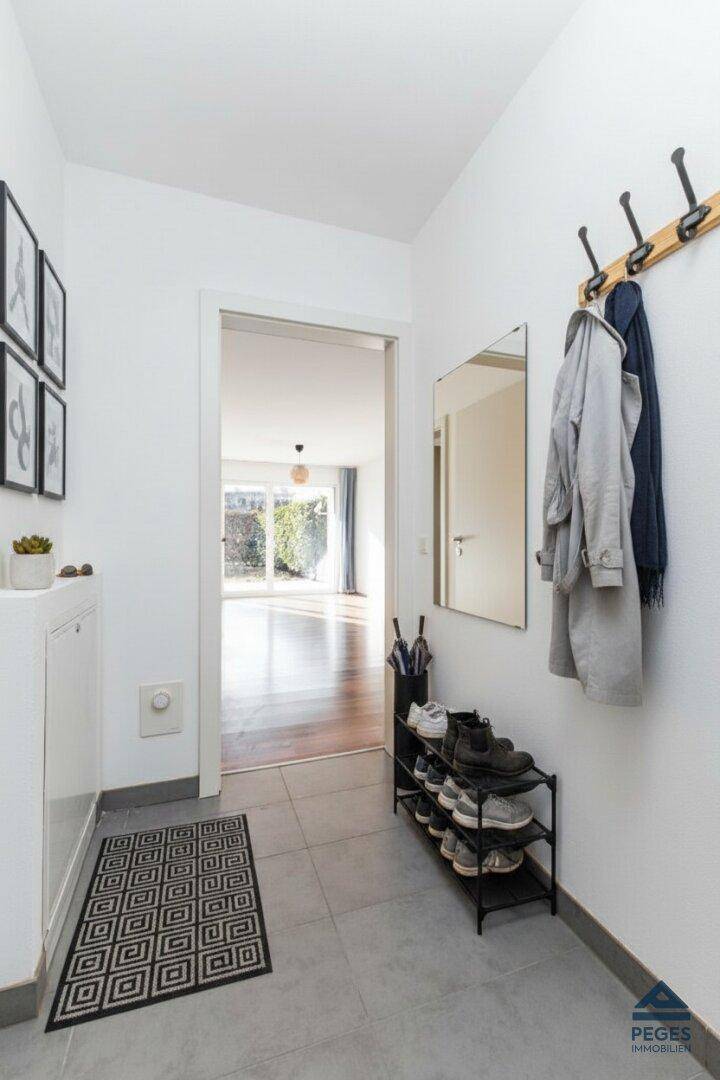 Heller Flur mit Garderobe, Spiegel und praktischem Schuhregal, führt in den Wohnbereich.
