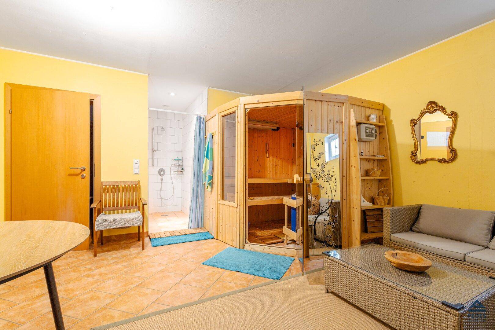 Gemütlicher Wellnessbereich mit Sauna, Dusche und Sitzgelegenheit zum Entspannen.