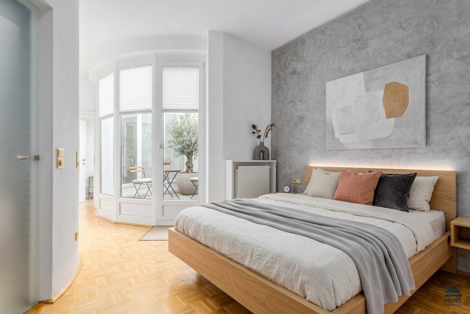 Modernes Schlafzimmer mit Holzbett, grauer Akzentwand und Zugang zu einem Außenbereich.