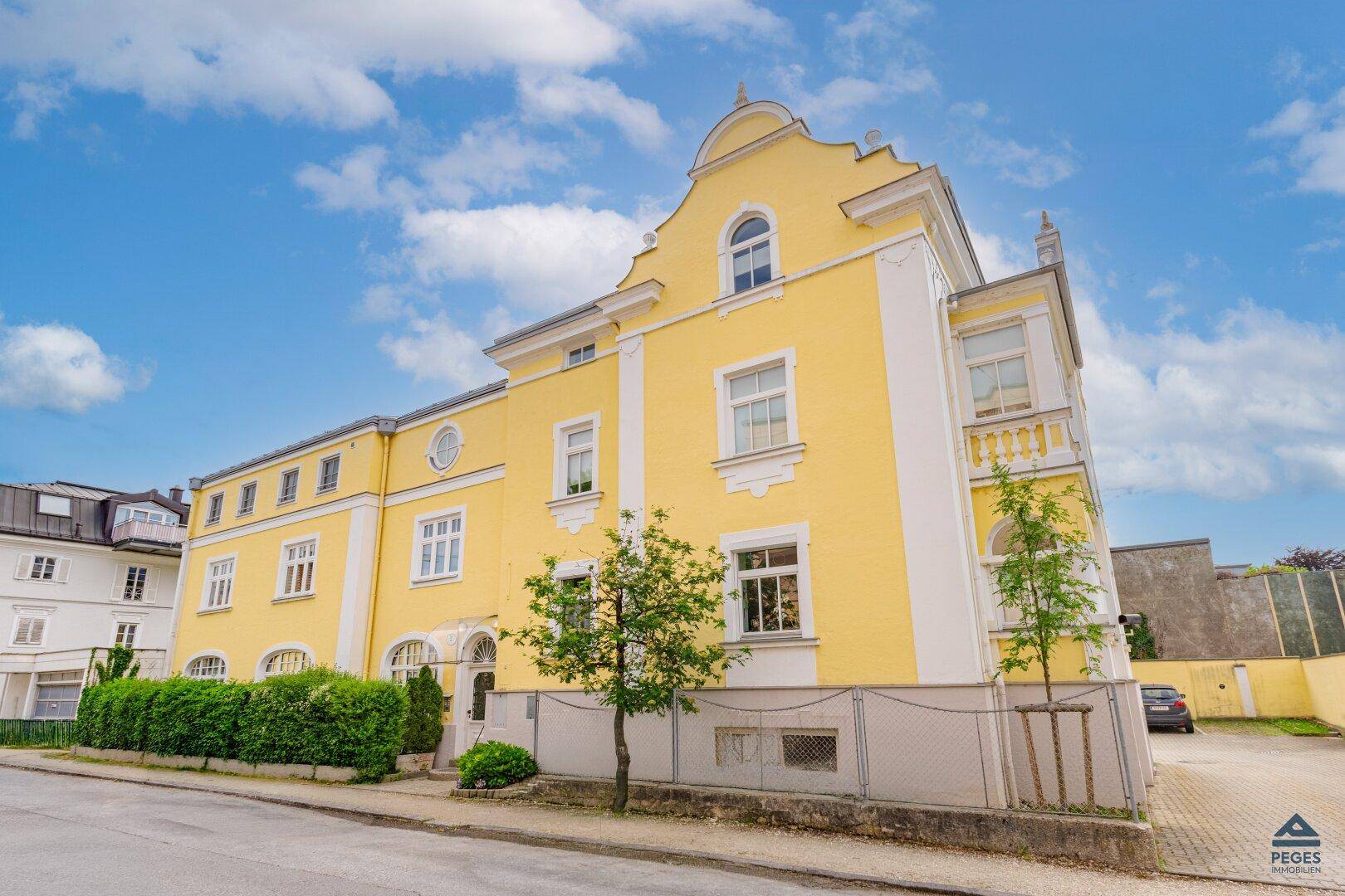 Historisches Gebäude mit gelber Fassade und klassischer Architektur an einer ruhigen Straße.