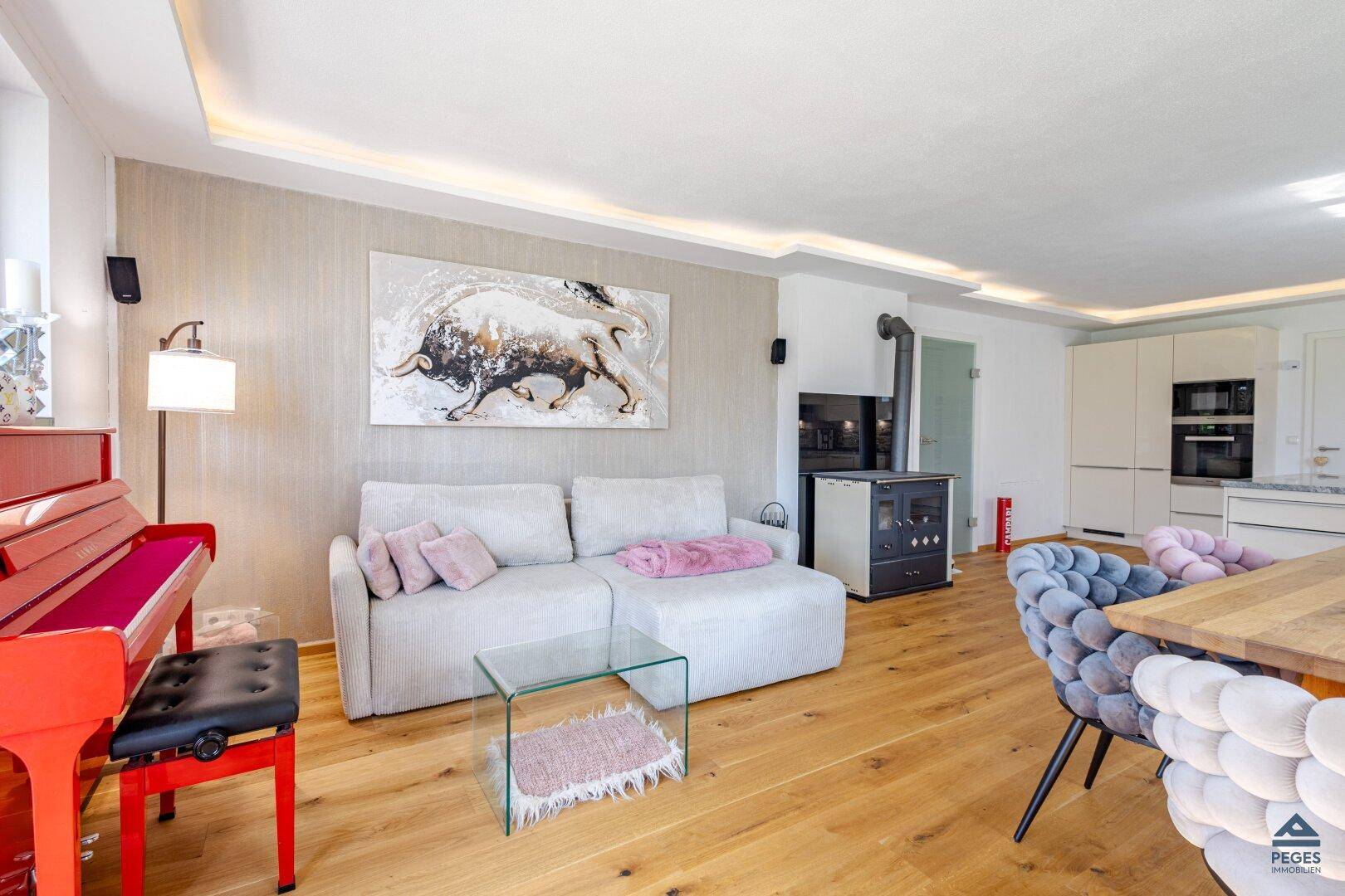 Heller Wohn- und Essbereich mit Holzboden, gemütlichem Sofa, Klavier und modernem Kaminofen.