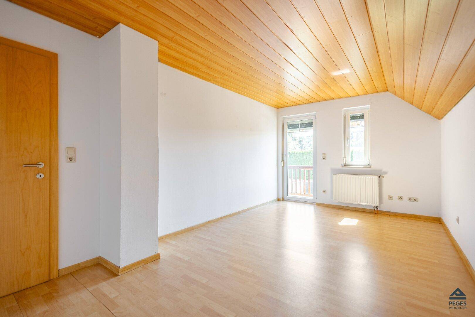 Geräumiges Zimmer mit Holzboden, Holzdecke und viel natürlichem Licht.