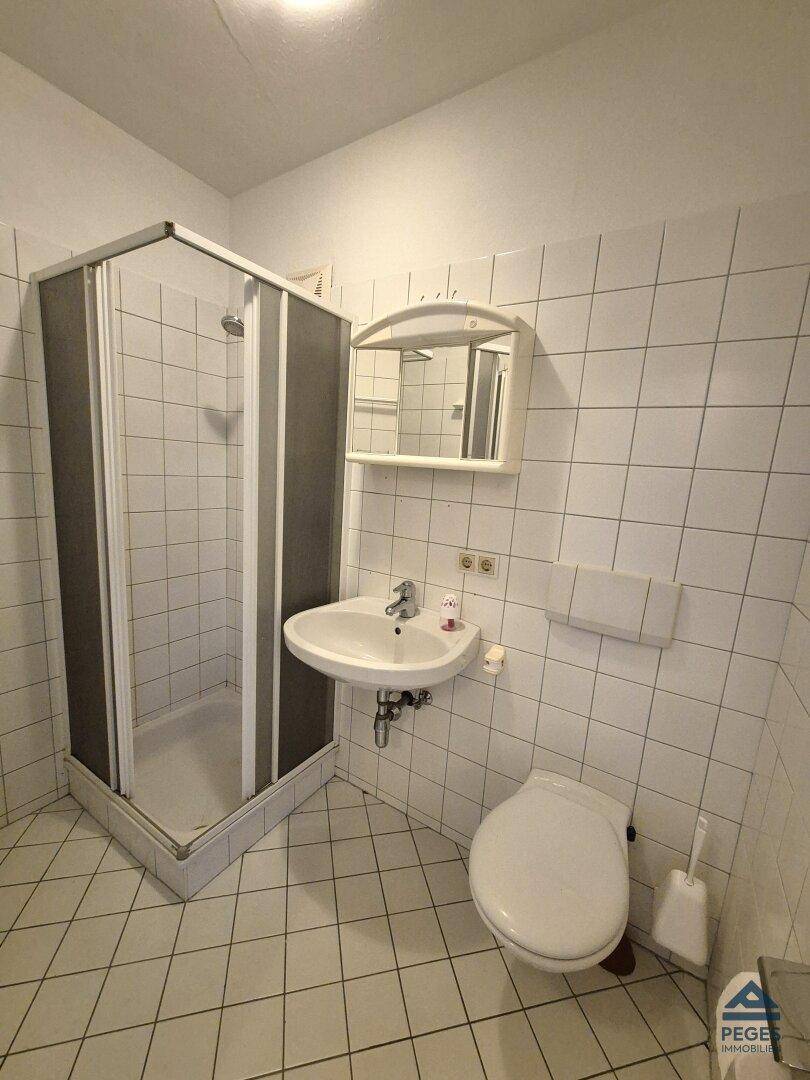 Funktionales Badezimmer mit Duschkabine, Waschbecken und Toilette, komplett gefliest.