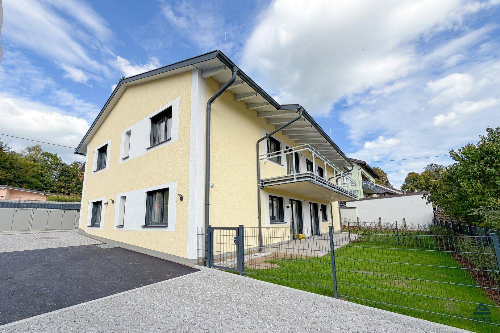 Attraktives gelbes Einfamilienhaus mit Balkonen, gepflegtem Vorgarten und moderner Architektur.