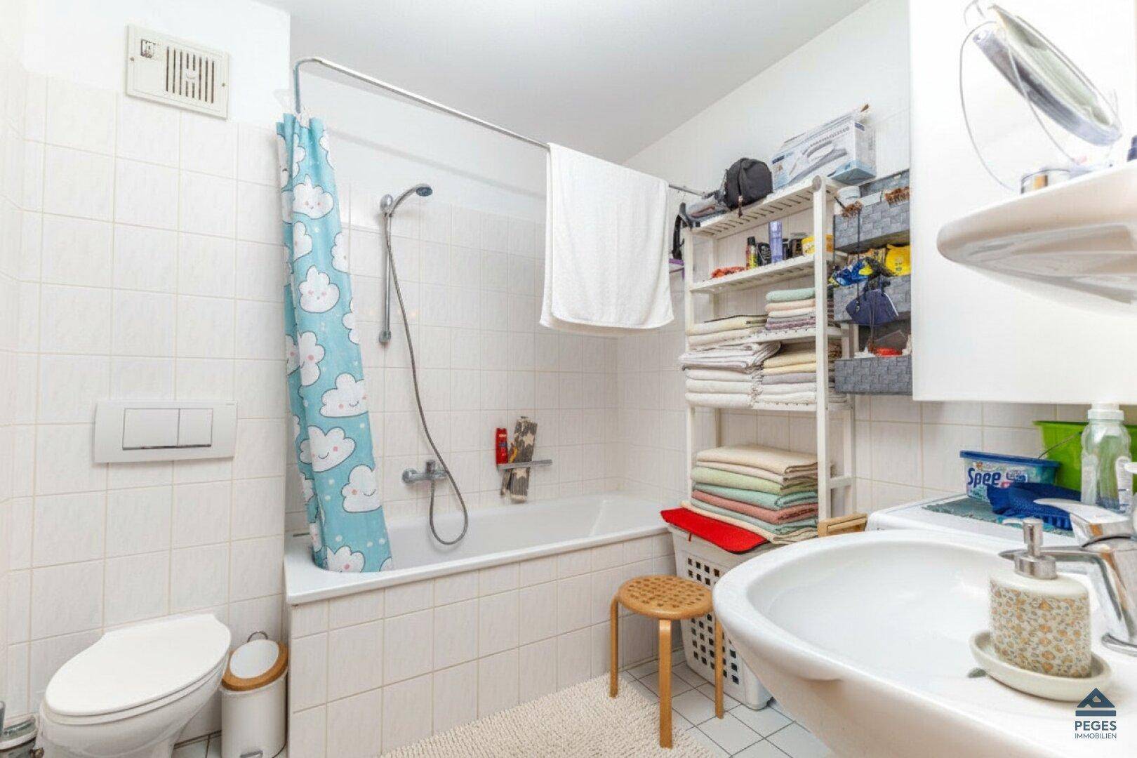 Funktionales Badezimmer mit Badewanne, Duschfunktion, WC und weißen Fliesen.