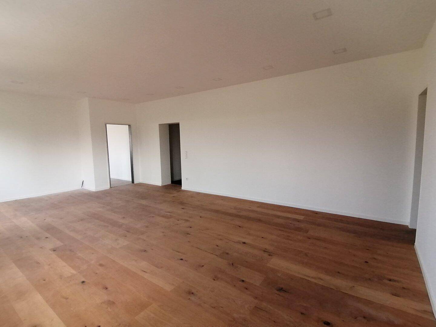 Heller, leerer Raum mit Holzboden und weißen Wänden, bereit zur individuellen Gestaltung.