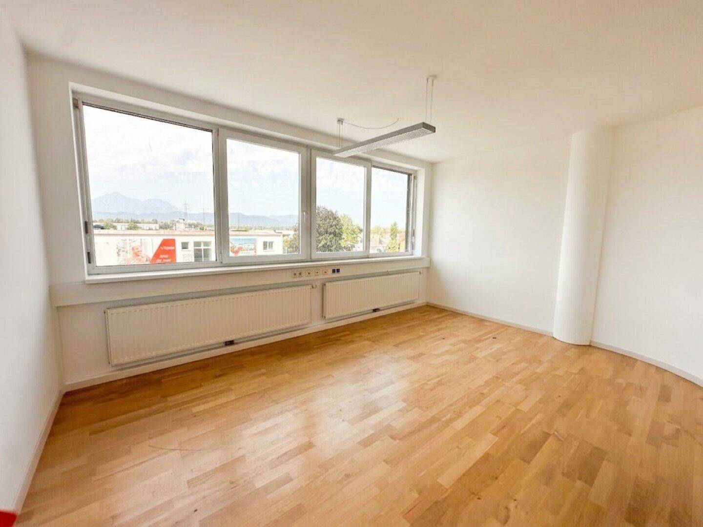 Geräumiger Büroraum mit viel Tageslicht, Parkettboden und weitem Ausblick auf die Umgebung.