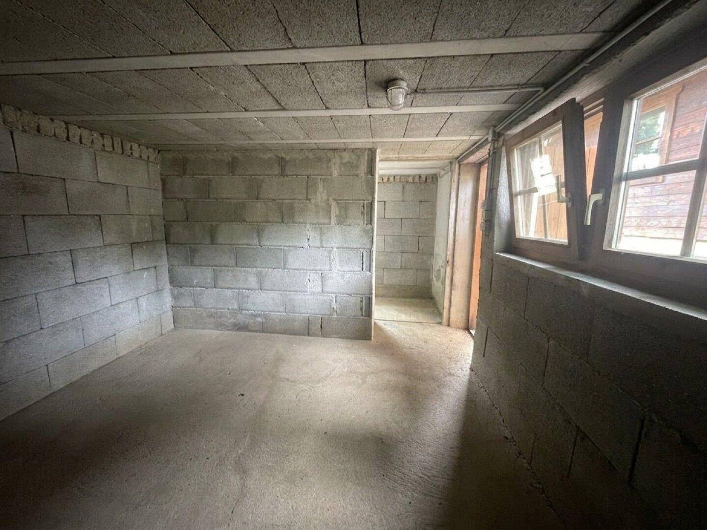 Unfertiger Kellerraum mit Betonwänden und einem kleinen Fenster, ideal als Abstellraum.