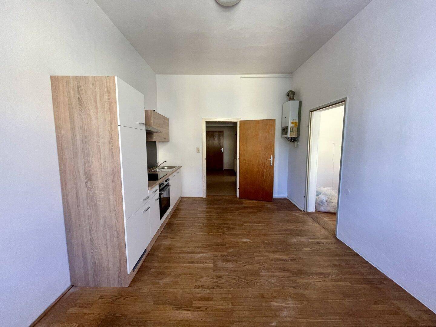 Funktionale Küchenzeile mit Holz- und Weißtönen, ausgestattet mit Herd und Dunstabzugshaube.
