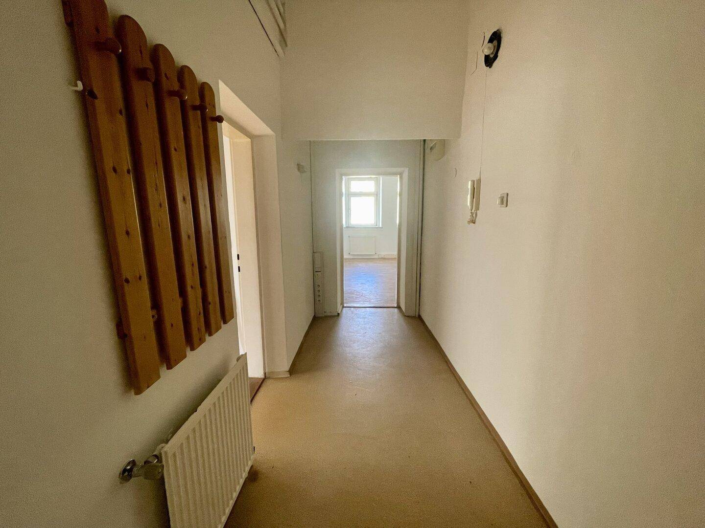 Heller Flur mit Garderobe und Heizkörper, der zu weiteren Räumen der Wohnung führt.