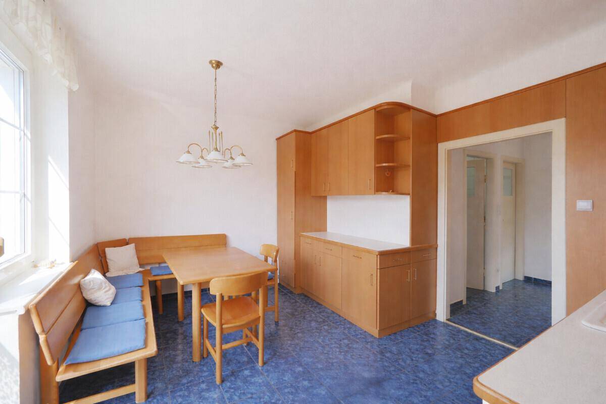 Wohnliche Küche mit Holzeinbauten, Essecke und blauen Fliesenboden.
