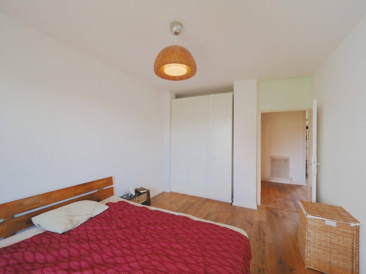 Schlafzimmer mit Holzboden, Doppelbett und weißen Einbauschränken.