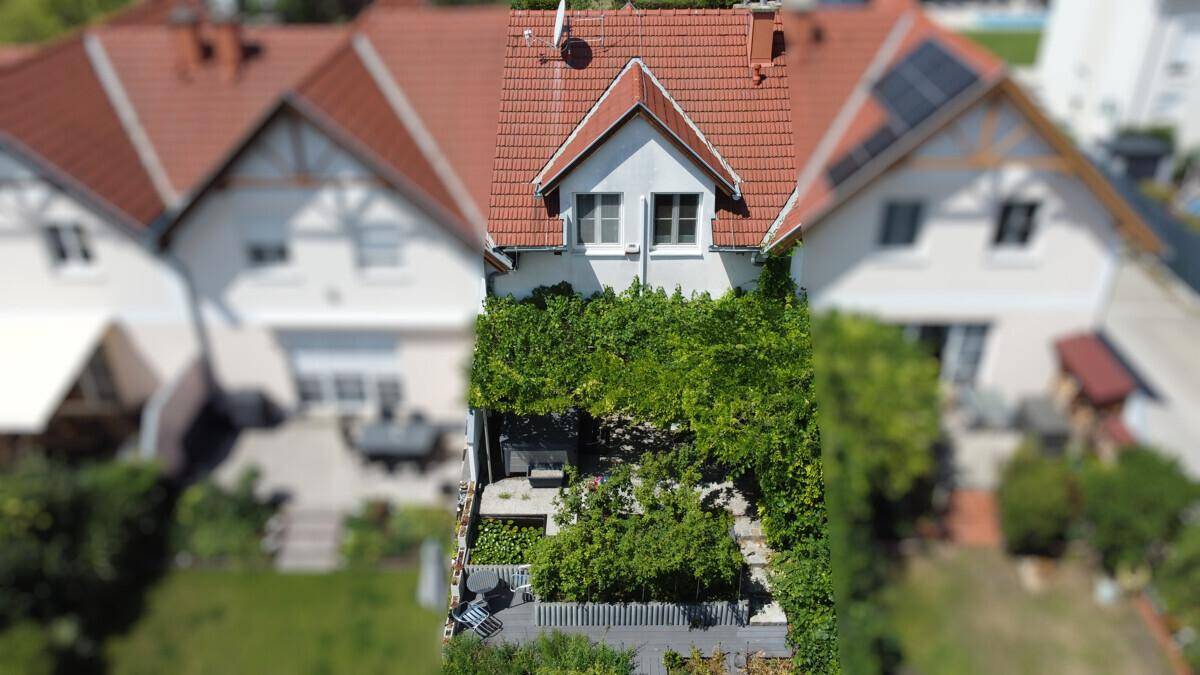 Vogelperspektive auf ein Reihenhaus mit üppig bewachsenem Garten und Terrasse.