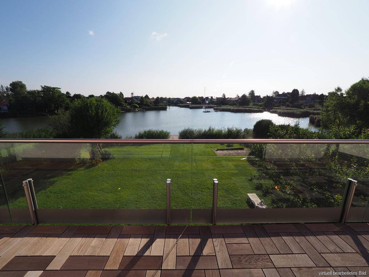 Geräumige Terrasse mit Holzboden und Glasgeländer bietet einen weiten Blick auf den See.