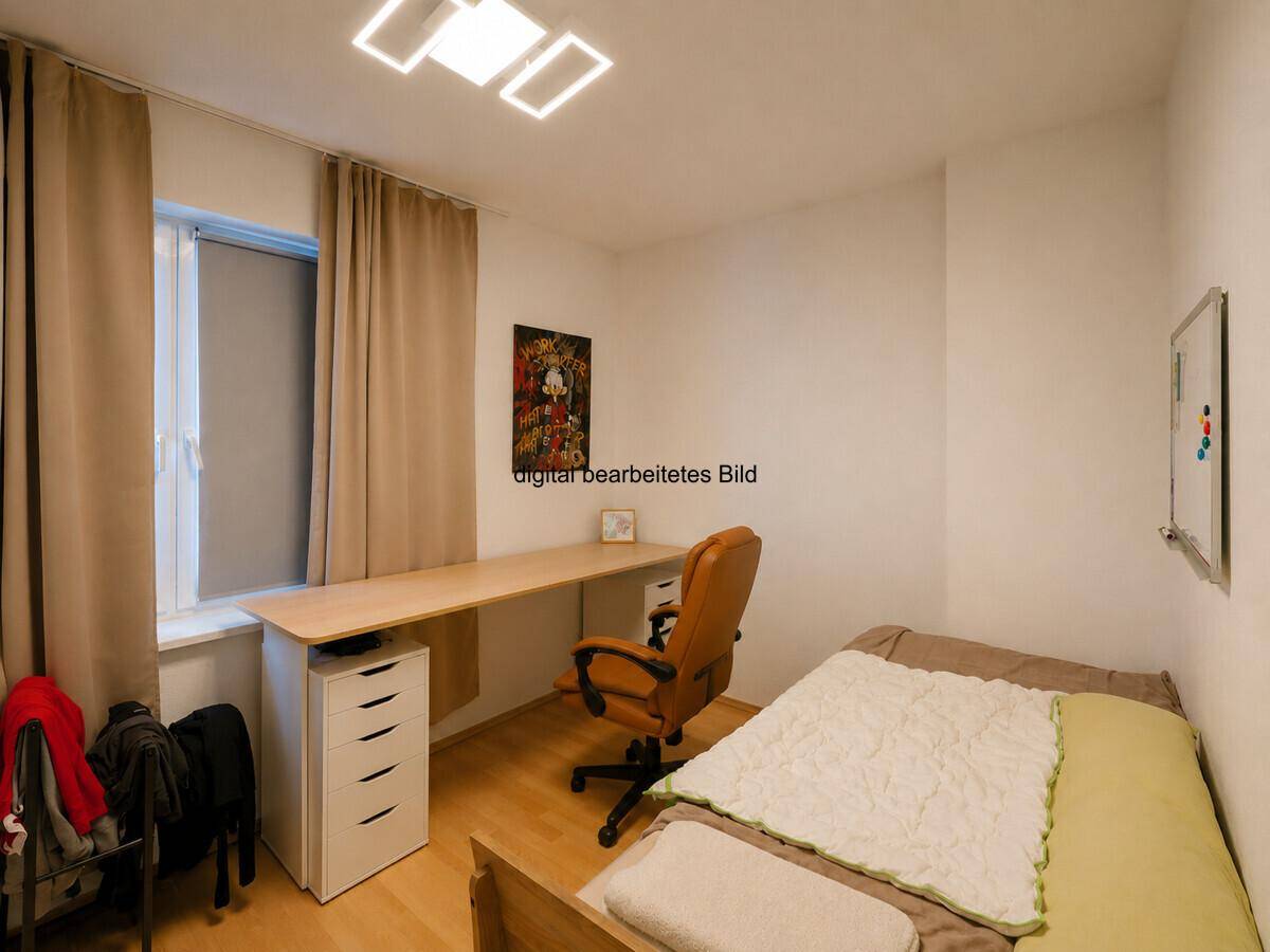 Helles Schlafzimmer mit Schreibtisch, Bett und Fenster, ideal als Arbeits- oder Gästezimmer.