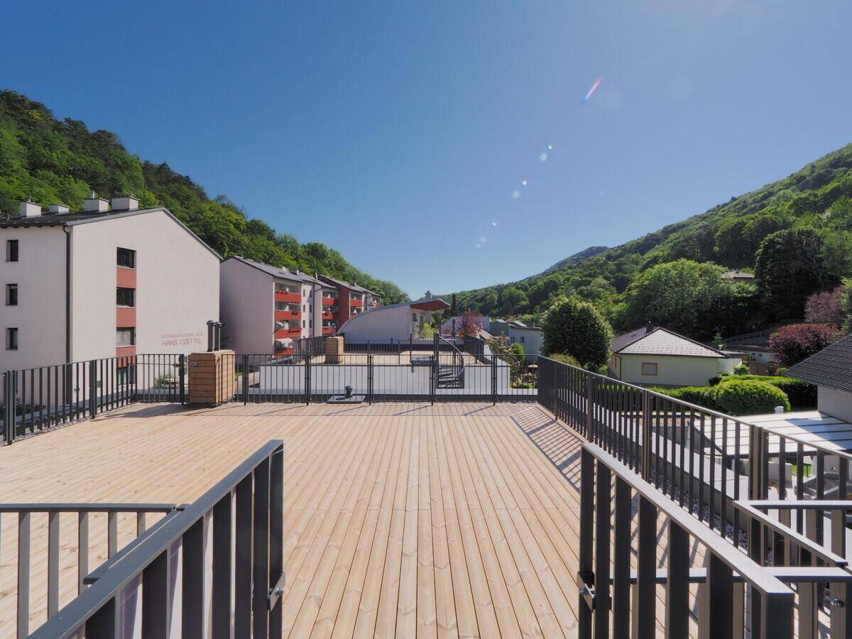 Große Dachterrasse aus Holz mit Metallgeländer und weitem Blick auf die umliegende Landschaft.