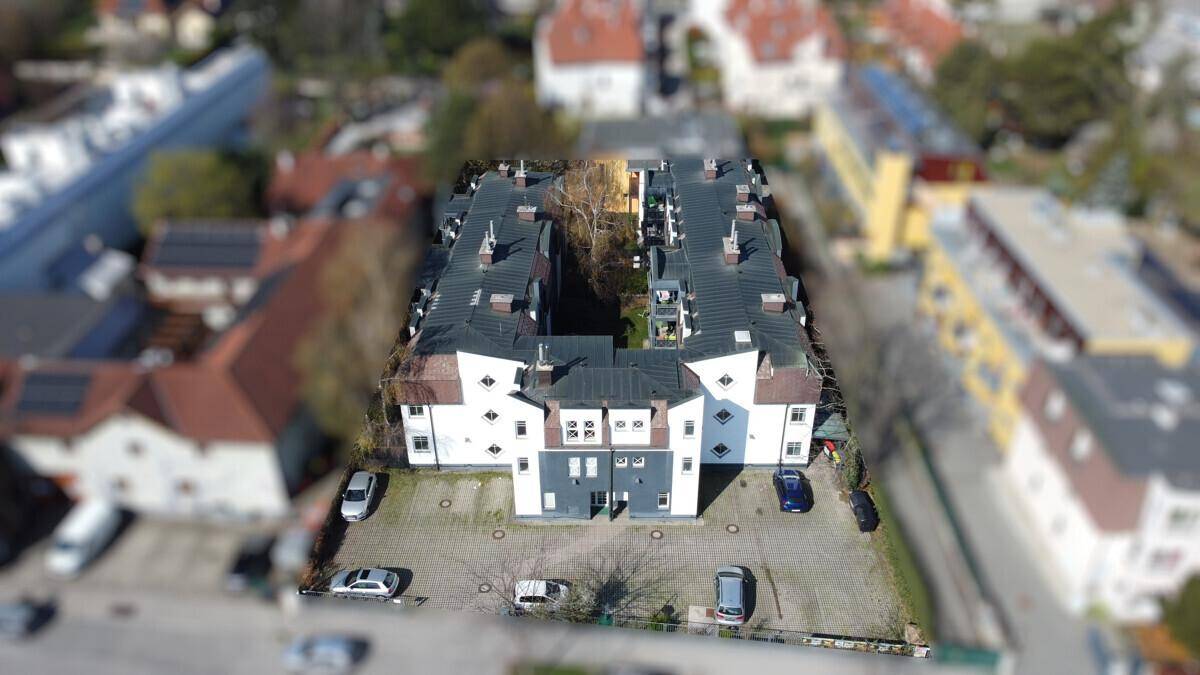 Luftaufnahme des modernen Wohnkomplexes mit Innenhof und umliegender Bebauung.