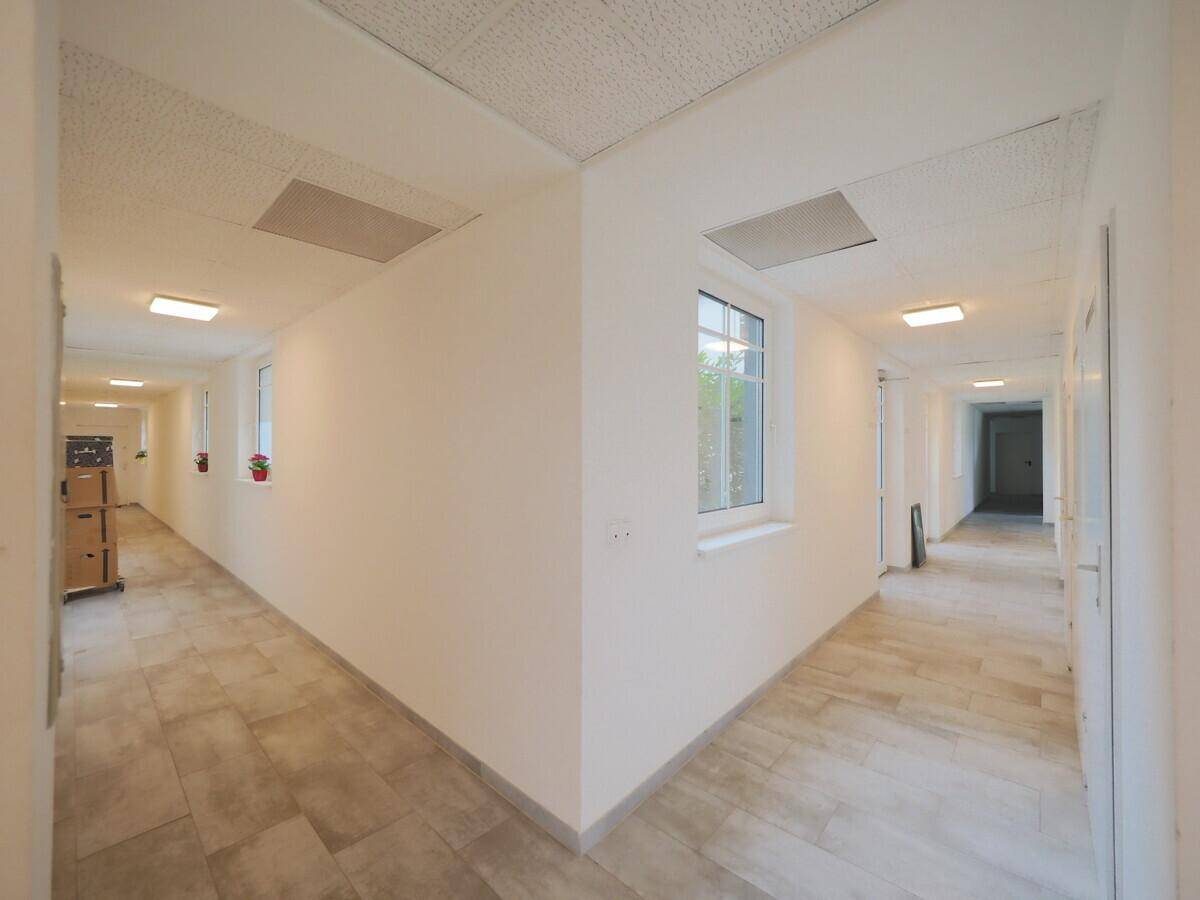 Langer, heller Flur mit Fenstern und Fliesenboden, der viel Tageslicht hereinlässt.