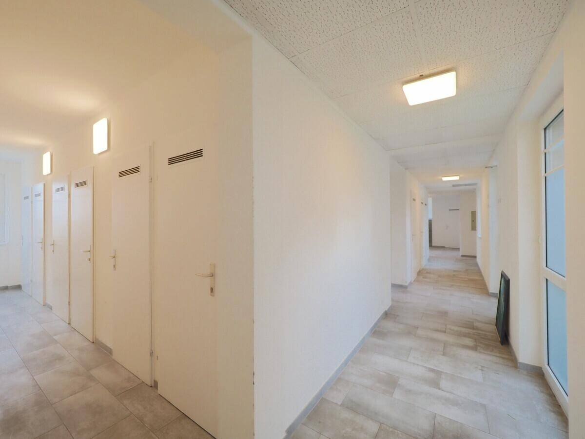 Heller Flur mit Fenstern, Fliesenboden und Zugang zu verschiedenen Wohnungen.