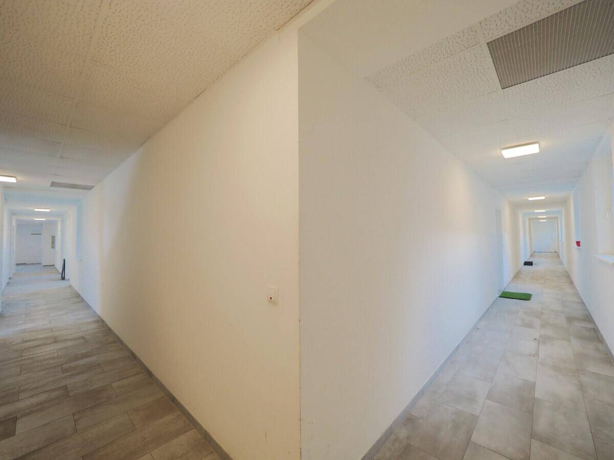 Langer, heller Flur mit Fliesenboden und mehreren Türen zu den Wohneinheiten.