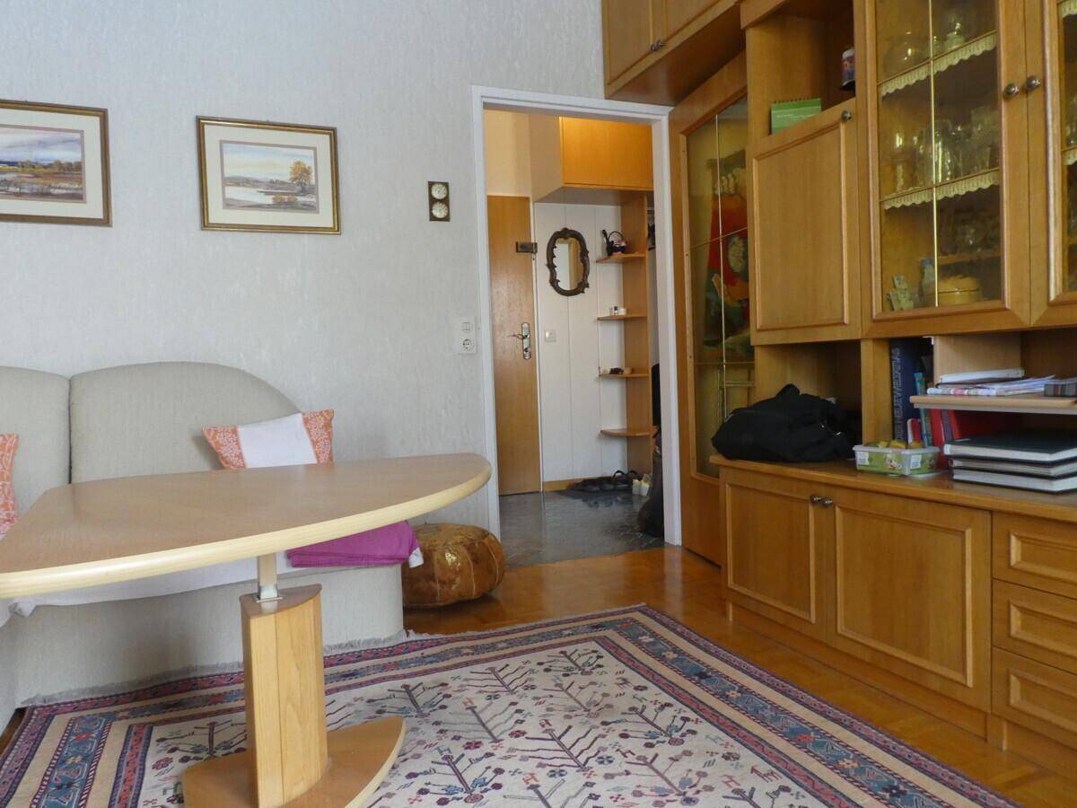 Wohnzimmer mit Holzeinbauschrank und Blick in den Flur, der zu weiteren Räumen führt.
