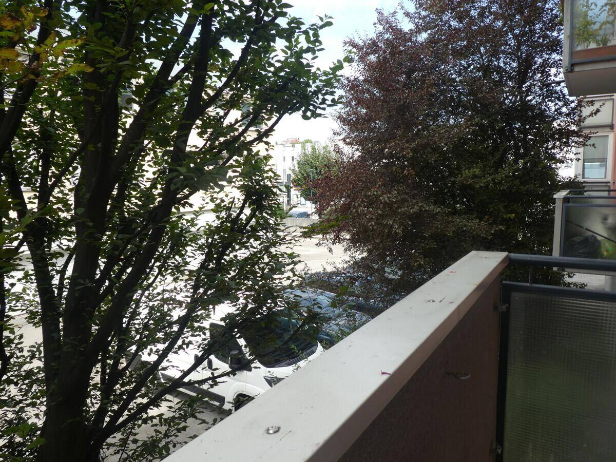 Balkon mit Blick auf die Straße und umliegende Bäume, bietet eine grüne Aussicht.