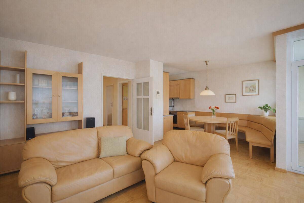Offener Wohnbereich mit beigen Sofas und Blick auf den Essbereich und die Küche im Hintergrund.