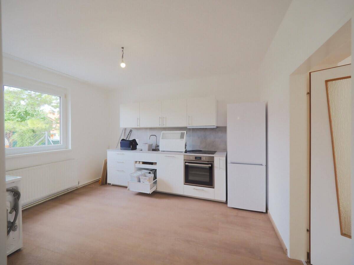Funktionale Küche mit weißen Einbauschränken, Kühlschrank und Induktionskochfeld, hell und praktisch.