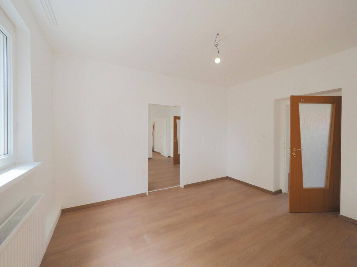 Geräumiges Zimmer mit Laminatboden, weißen Wänden und einem Fenster, das für gute Belichtung sorgt.