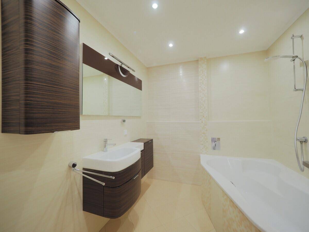 Modernes Badezimmer mit Badewanne, Doppelwaschbecken und dunklen Holzschränken.