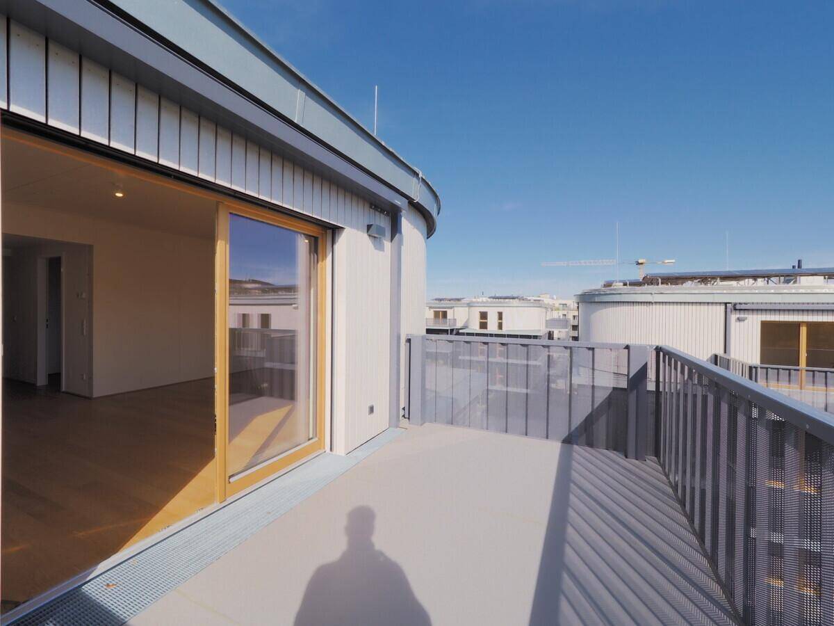 Heller Balkon mit Schiebetür zum Innenraum und modernem Geländer.