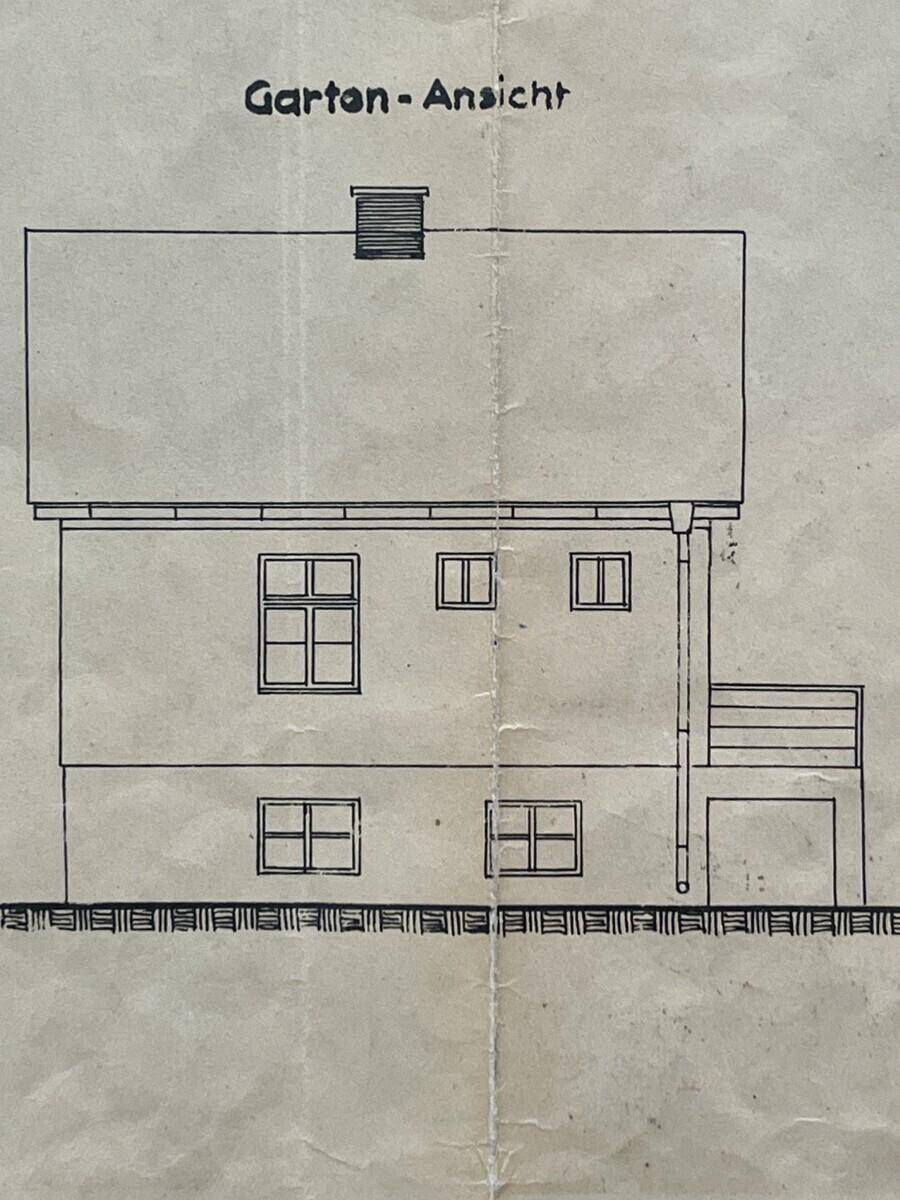 Ansicht des Hauses von der Gartenseite mit mehreren Fenstern und Balkon.