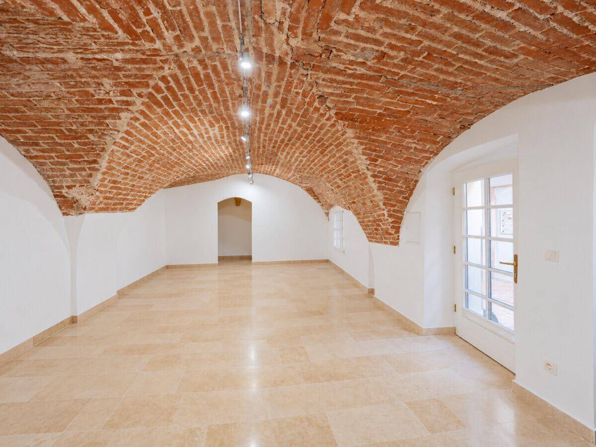 Historischer Raum mit Ziegelgewölbedecke und großen Fenstertüren, die viel Licht hereinlassen.