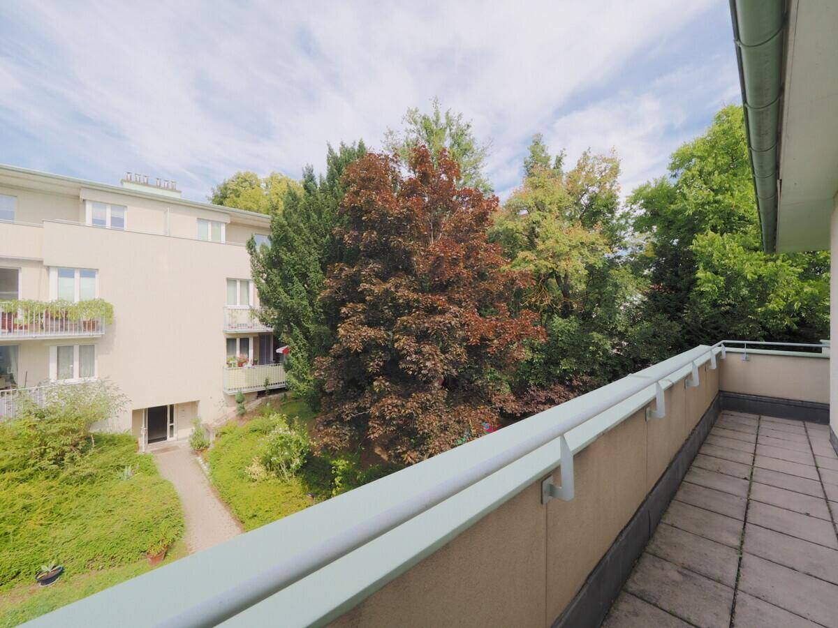 Balkon mit Ausblick auf den gepflegten Innenhof und die grüne Gartenanlage.