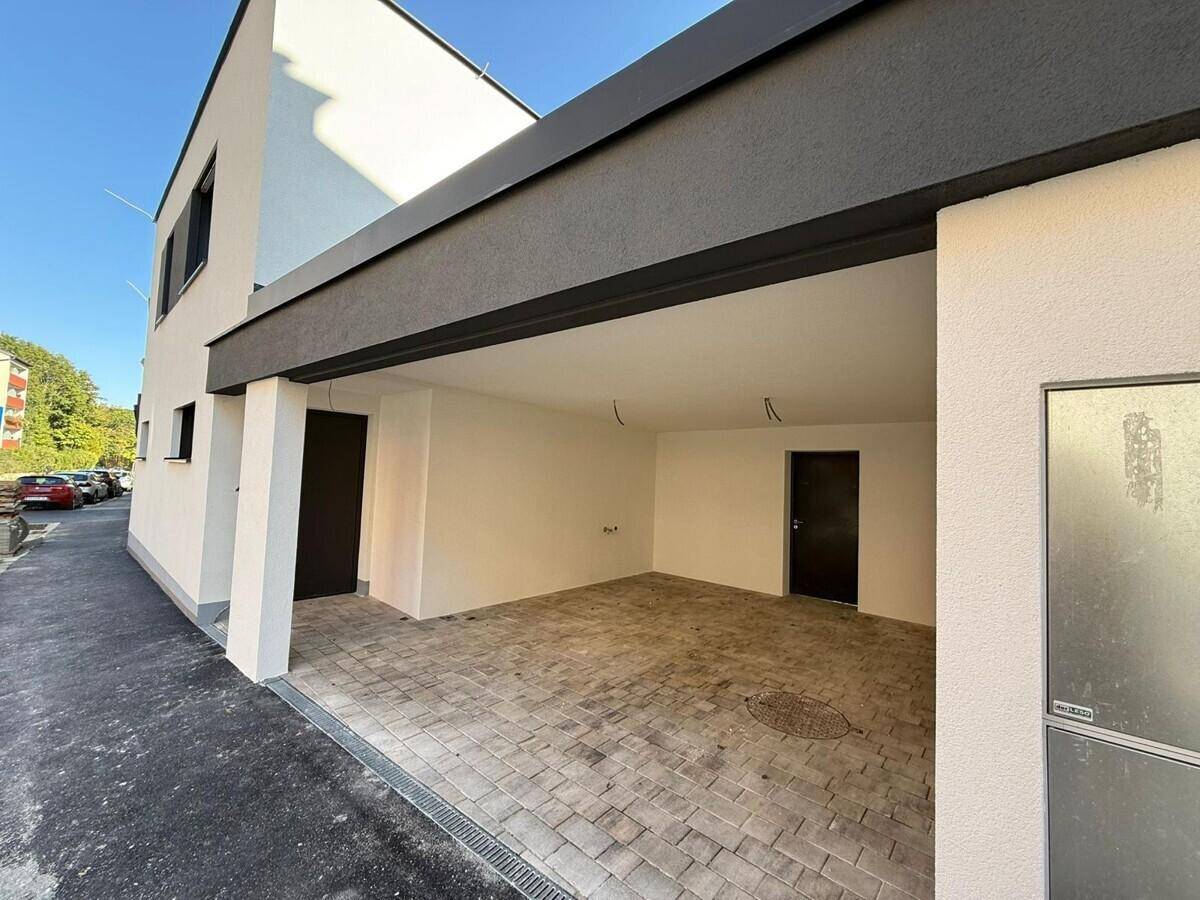 Geräumiger Carport mit gepflastertem Boden und direktem Zugang zum Haus.