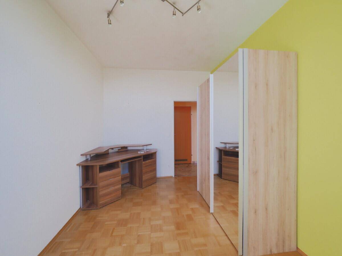 Geräumiges Zimmer mit Parkettboden und einem Schrank mit Spiegeltüren, ideal als Büro.