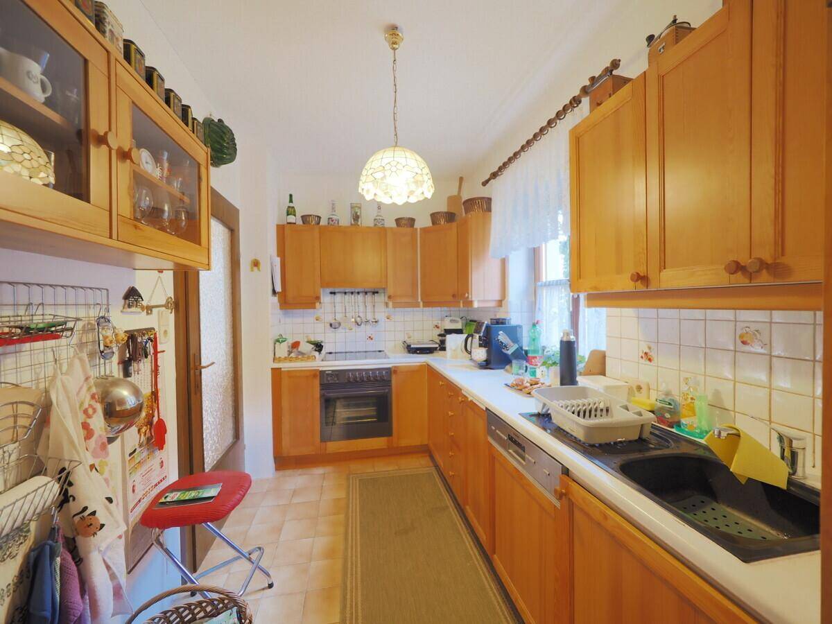 Funktionale Küche mit Holzschränken, weißen Fliesen und einem Fenster für natürliches Licht.